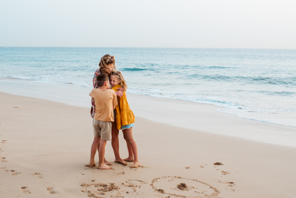 Mother with two kids on beach. Young family enjoying sandy beach, looking at crystalline sea in Canary Islands. Concept of a beach summer vacation with kids.