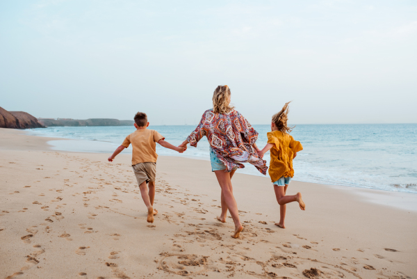 Mother with two kids on beach. Young family enjoying sandy beach in Canary Islands. Concept of a beach summer vacation with kids.