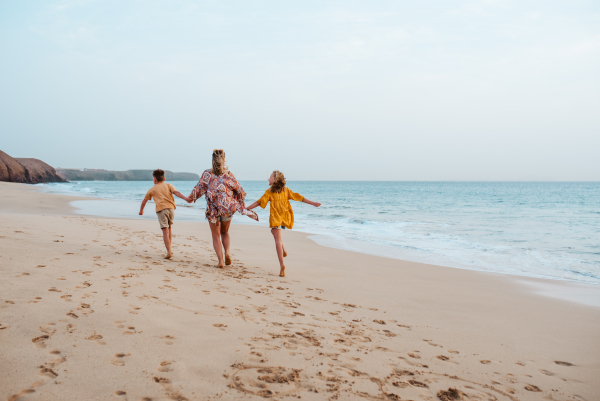 Mother with two kids on beach. Young family enjoying sandy beach in Canary Islands. Concept of a beach summer vacation with kids.