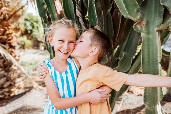 Portrait of siblings on summer vacation in holiday destination. Happy brother kissing sister on cheek. Concept of a family beach summer vacation with kids.