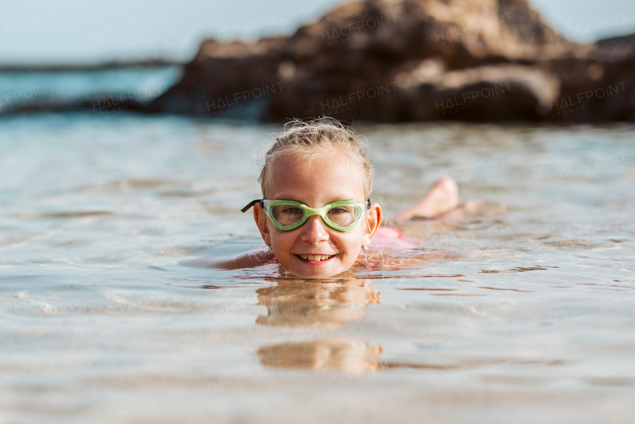 Young girl on the beach. Smilling blonde girl enjoying sandy beach, looking at crystalline sea in Canary Islands. Concept of beach summer vacation with kids.