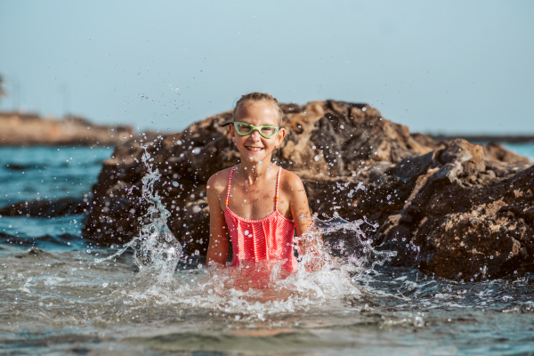 Young girl on the beach. Smilling blonde girl enjoying sandy beach, looking at crystalline sea in Canary Islands. Concept of beach summer vacation with kids.