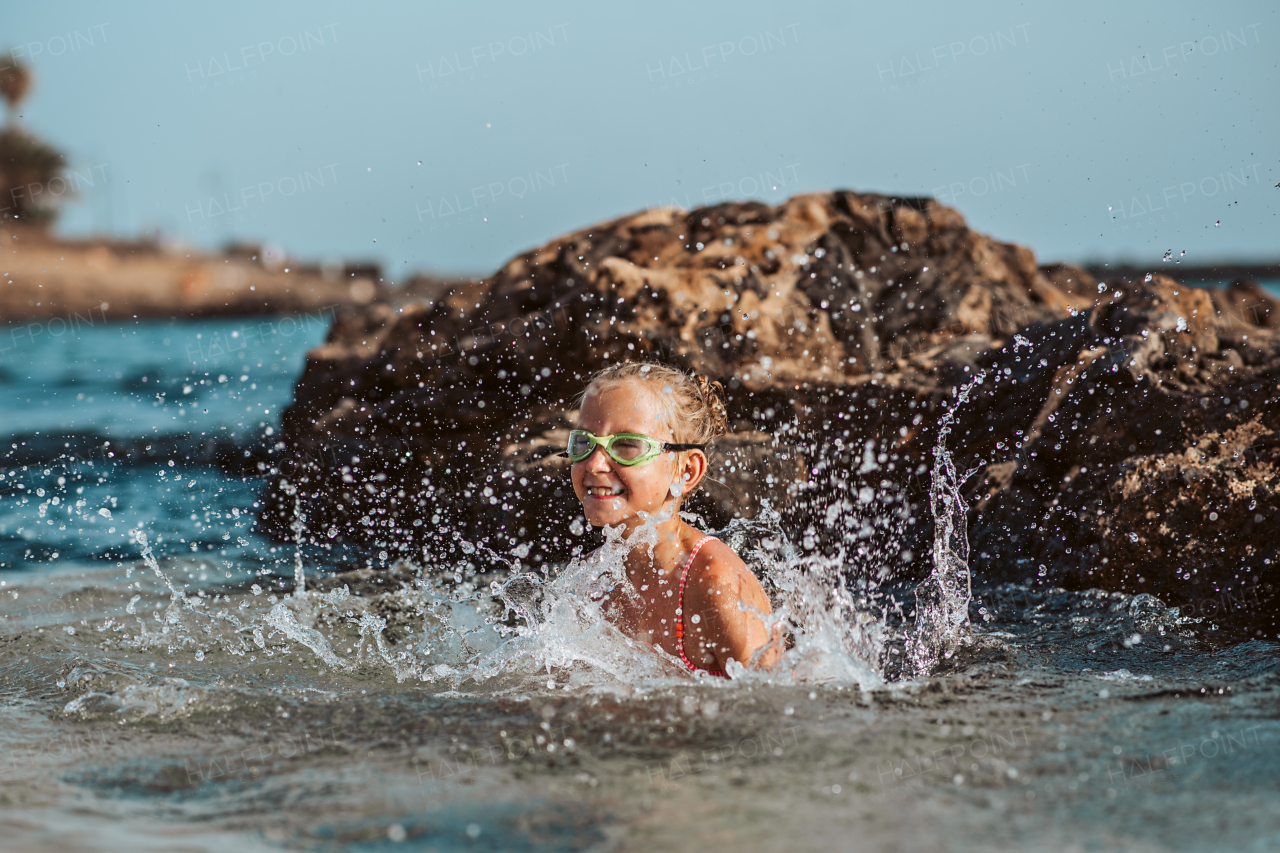 Young girl on the beach. Smilling blonde girl enjoying sandy beach, looking at crystalline sea in Canary Islands. Concept of beach summer vacation with kids.