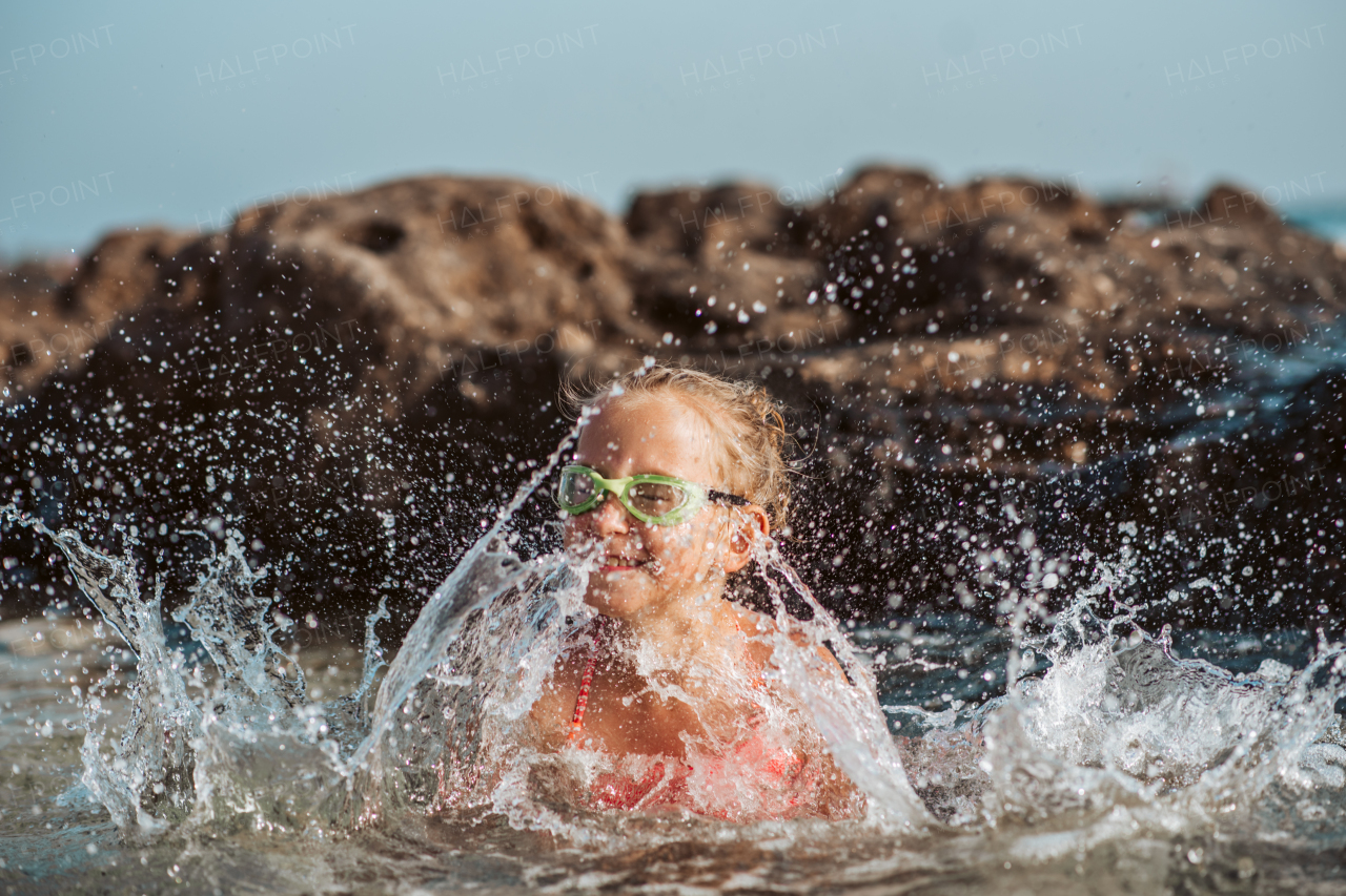 Young girl on the beach. Smilling blonde girl enjoying sandy beach, looking at crystalline sea in Canary Islands. Concept of beach summer vacation with kids.