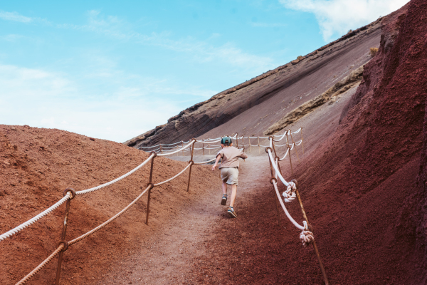 Boy running up the hill. Family exploring new places during summer vacation on Canary islands, Lanzarote.