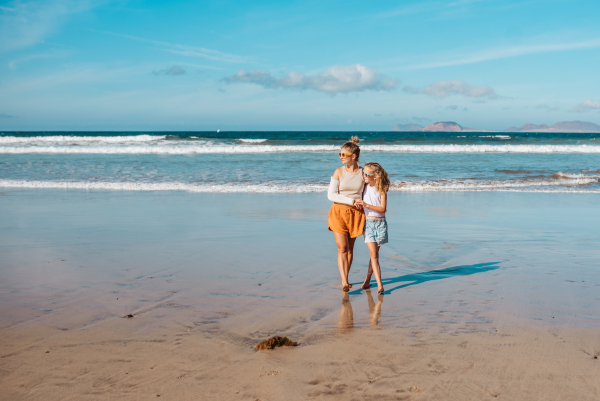 Daughter with mother with broken arm on beach. Arm cast, injured during family vacation in holiday resort. Concept of family beach summer vacation with injury.