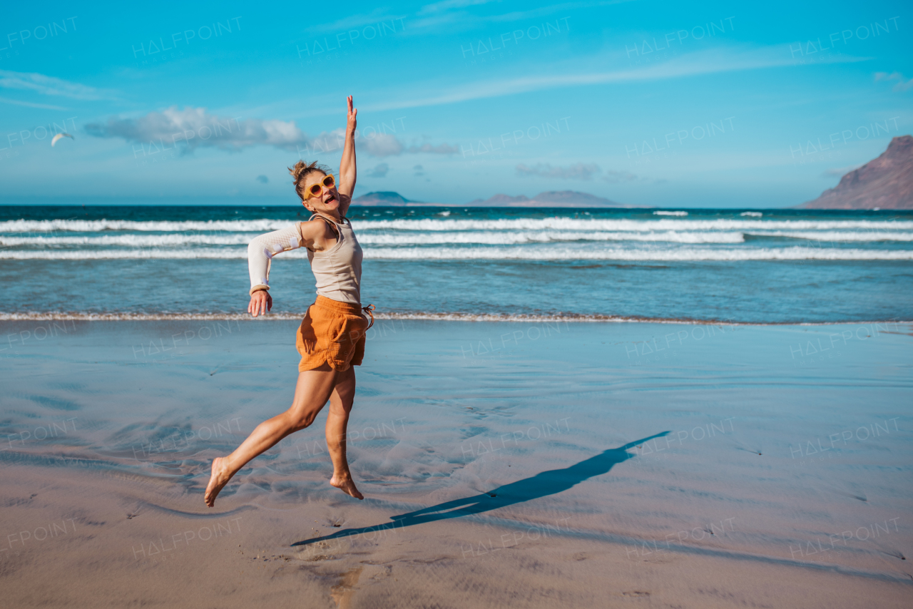 Beautiful woman with broken arm on beach. Arm cast, injured during family vacation in holiday resort. Concept of beach summer vacation.