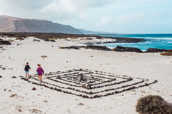 Siblings on walk at Canary islands beach. Concept of family beach summer vacation with kids. Minimalistic shot from high angle.