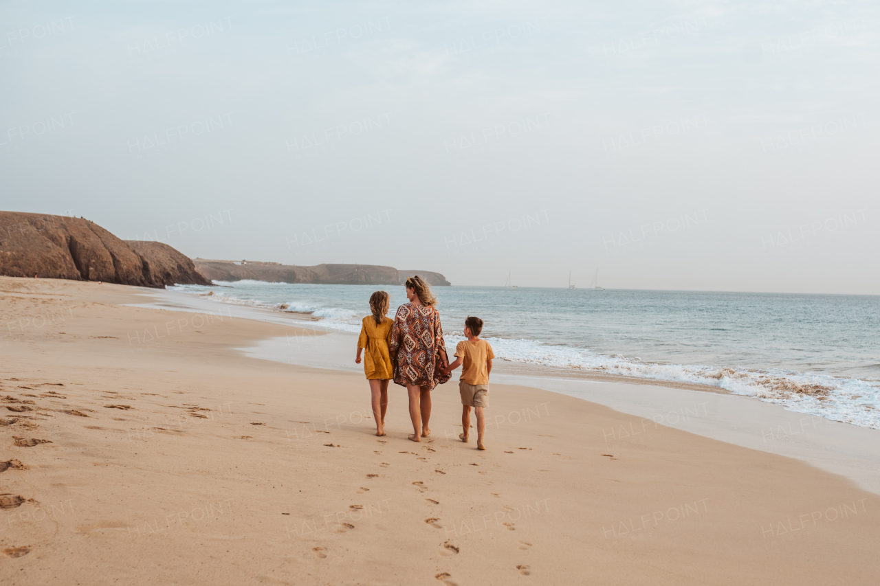 Mother with two kids on beach. Young family enjoying sandy beach in Canary Islands. Concept of a beach summer vacation with kids.