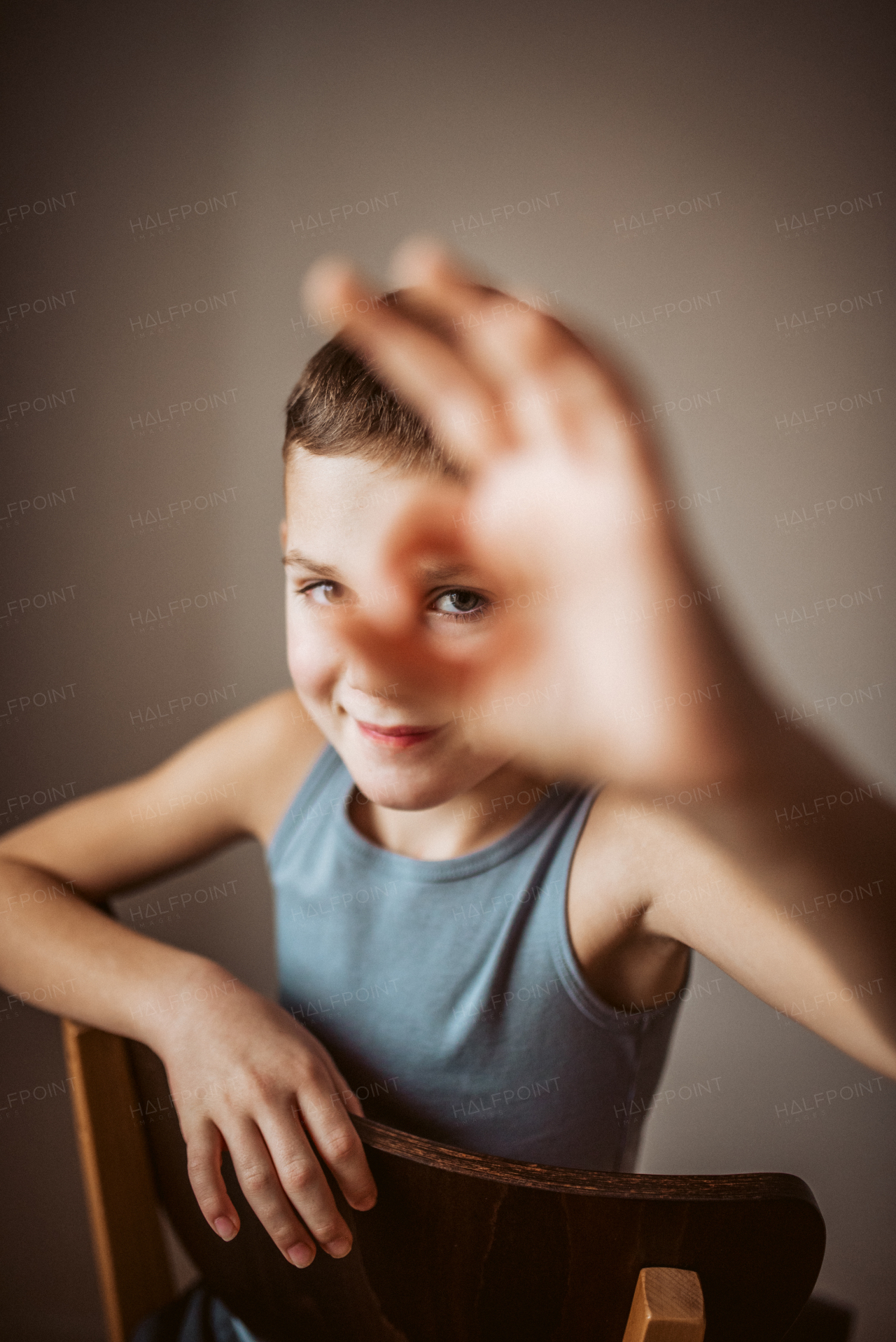 Portrait of a smiling boy looking at the camera through his fingers. OK sign made with fingers, circle from index finger and thumb.