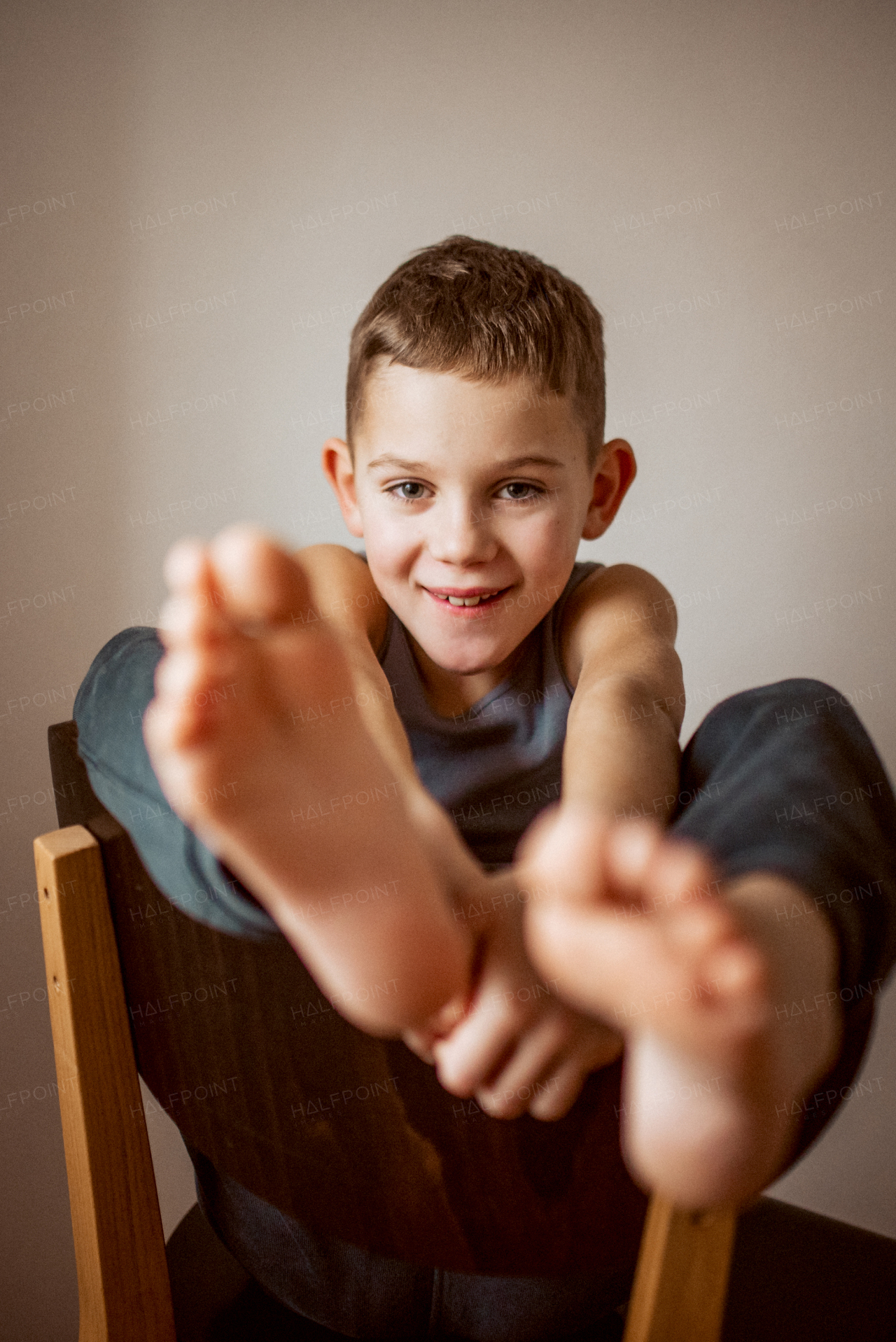 Portrait of a boy sitting on a chair with his legs propped up.