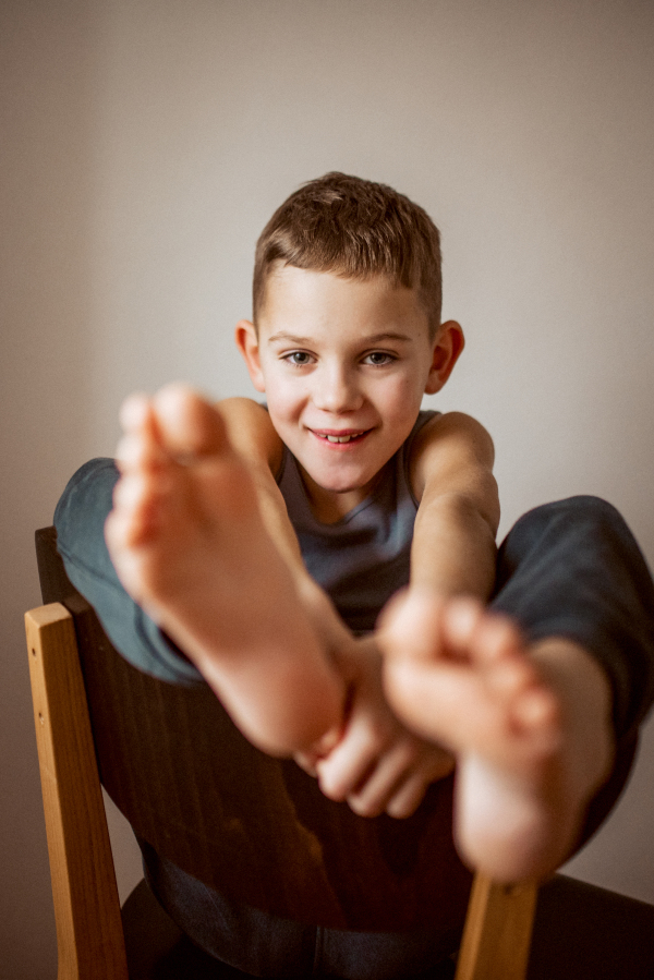 Portrait of a boy sitting on a chair with his legs propped up.