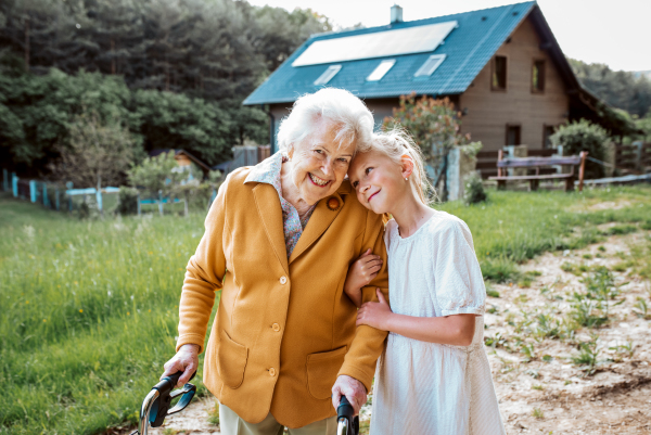 Granddaughter spending time with elderly grandma, companionship. Senior lady with walker on walk with young girl.