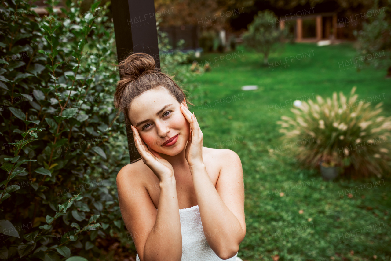 Beautiful woman resting in the garden after using home sauna. Woman taking care of her body and mind, wellness routine