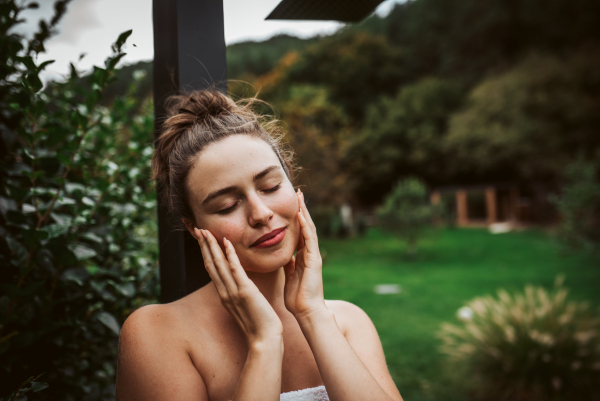 Beautiful woman resting in the garden after using home sauna. Woman taking care of her body and mind, wellness routine