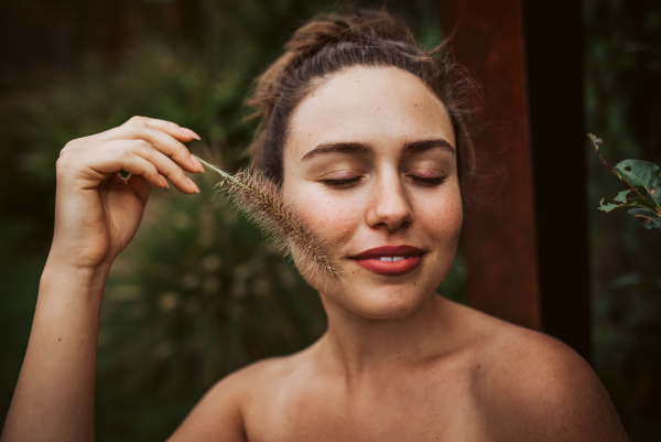 Portrait of a beautiful woman standing in a garden, holding a ornamental grass in her hand. Mental well-being and connection with nature