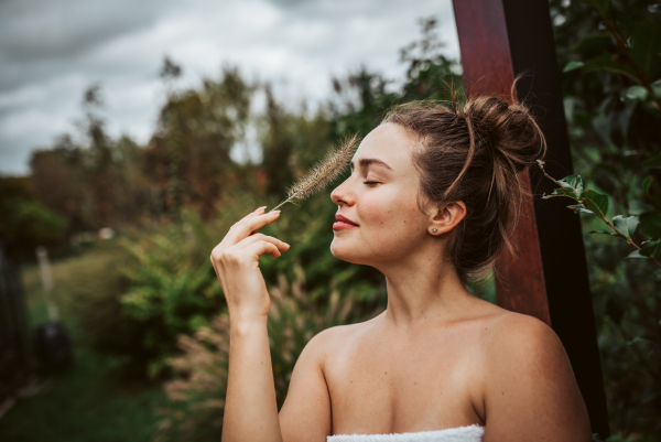 Portrait of a beautiful woman standing in a garden, holding a ornamental grass in her hand. Mental well-being and connection with nature