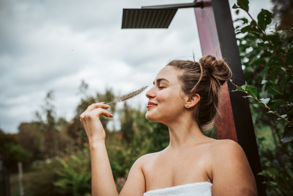 Portrait of a beautiful woman standing in a garden, holding a ornamental grass in her hand. Mental well-being and connection with nature