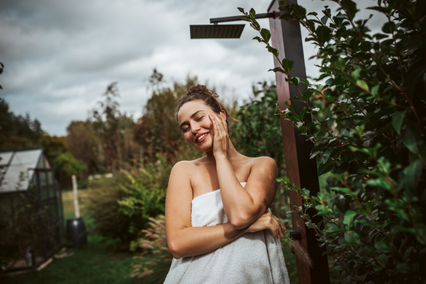 Beautiful woman resting in the garden after using home sauna. Woman taking care of her body and mind, wellness routine