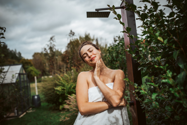 Beautiful woman resting in the garden after using home sauna. Woman taking care of her body and mind, wellness routine