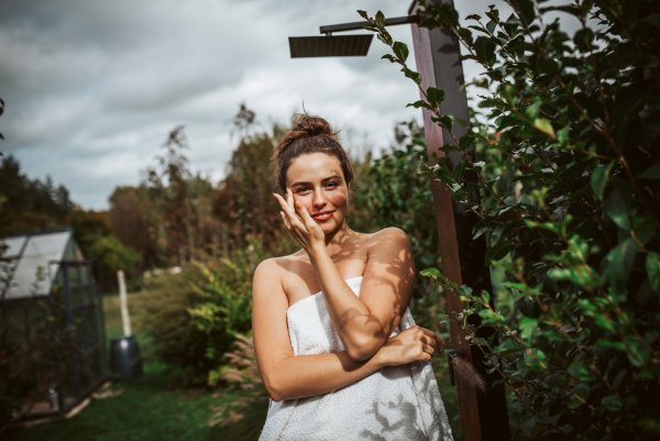 Beautiful woman resting in the garden after using home sauna. Woman taking care of her body and mind, wellness routine