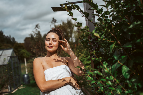 Beautiful woman resting in the garden after using home sauna. Woman taking care of her body and mind, wellness routine