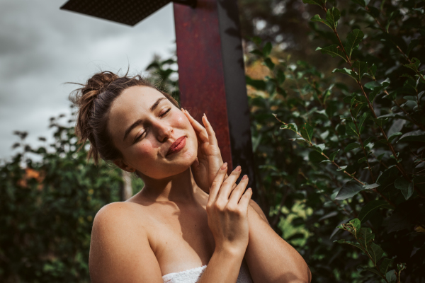 Beautiful woman resting in the garden after using home sauna. Woman taking care of her body and mind, wellness routine