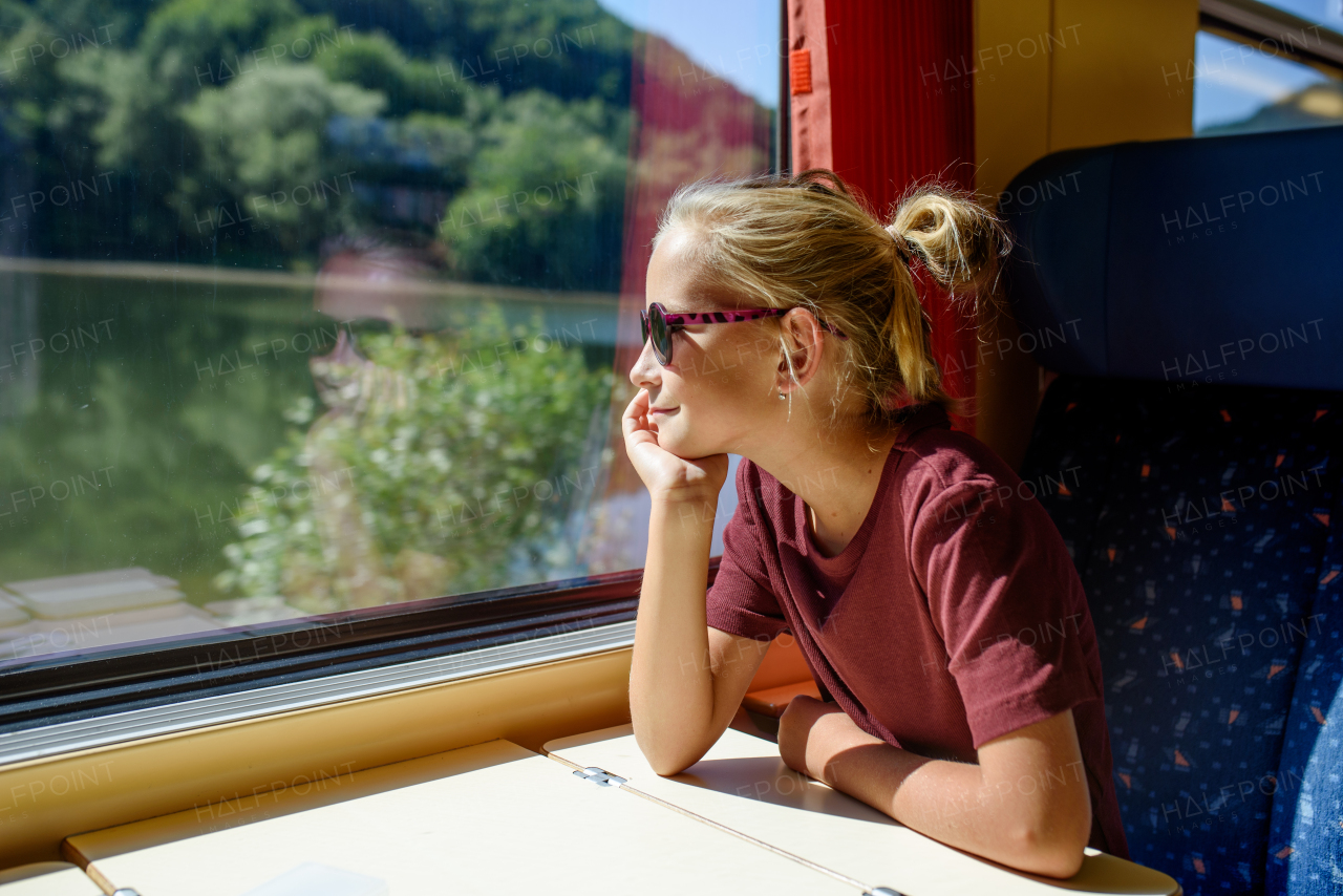 Girl sitting in train, looking out of window and enjoying journey. Family going on hike, using a public transport.