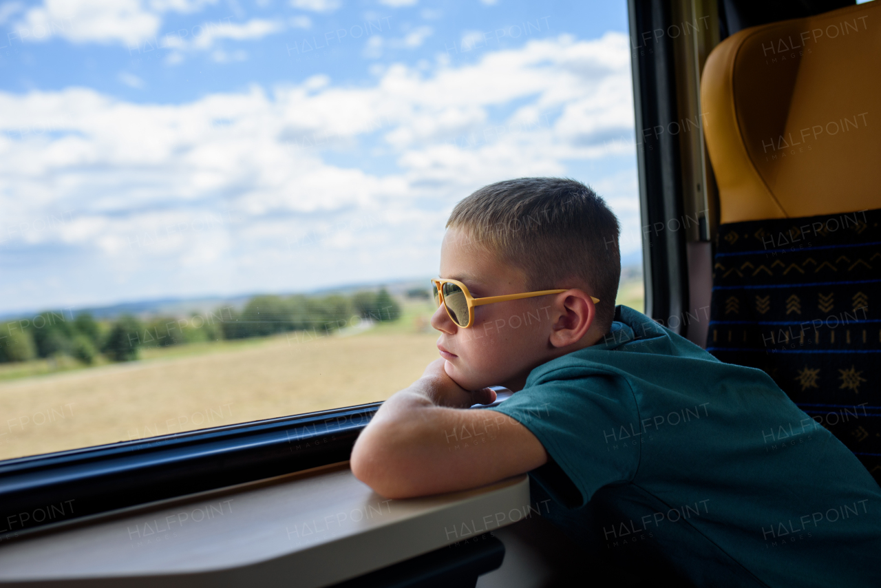 Boy sitting in train, looking out of window and enjoying journey. Family going on hike, using a public transport.