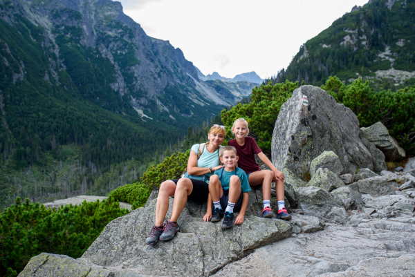 Grandmother with grandchildren on hike in autumn mountains. Kids spending summer break in nature with a family.