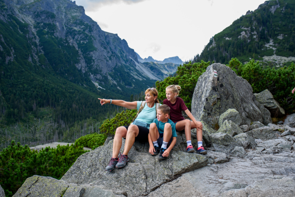 Grandmother with grandchildren on hike in autumn mountains. Kids spending summer break in nature with a family.