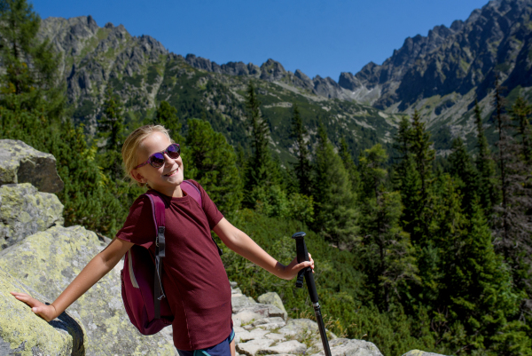 Cute girl with sunglasses on hike in autumn mountains. Kids spending time, summer break in nature.