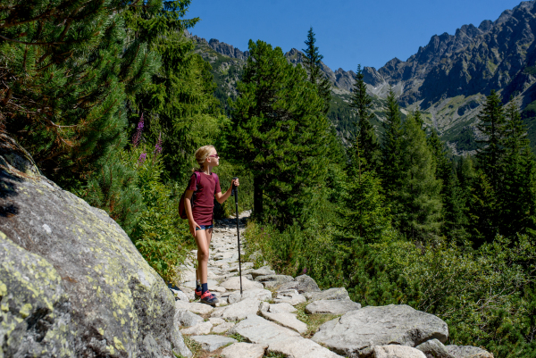 Cute girl with sunglasses on hike in autumn mountains. Kids spending time, summer break in nature.