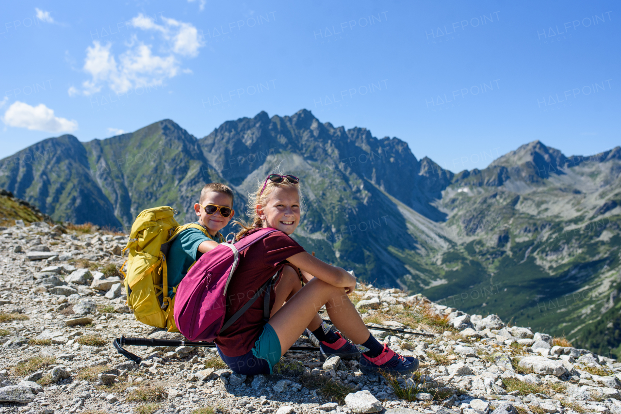 Siblings hiking together in autumn mountains, sitting on rocks and resting. Kids spending time, summer break in nature.