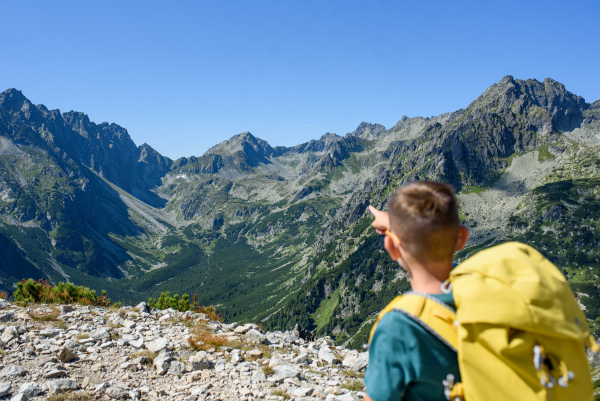 Boy on hike in autumn mountains. Kids spending time, summer break in nature. Rear view.