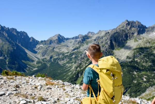 Boy on hike in autumn mountains. Kids spending time, summer break in nature. Rear view.