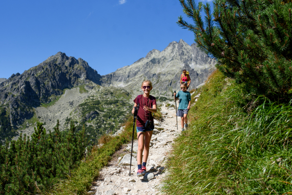 Grandmother with grandchildren on hike in autumn mountains. Kids spending summer break in nature with a family.