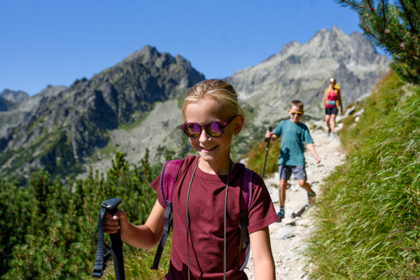 Grandmother with grandchildren on hike in autumn mountains, walking down the hiking trail. Kids spending summer break in nature with a family.