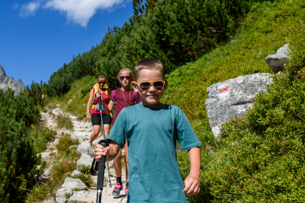 Grandmother with grandchildren on hike in autumn mountains. Kids spending summer break in nature with a family.