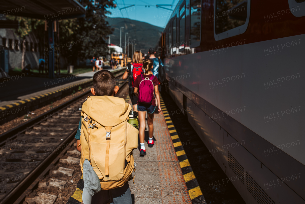 Grandma with grandchildrenboarding the train, walking on platform. Family going on hike, using the public transport.