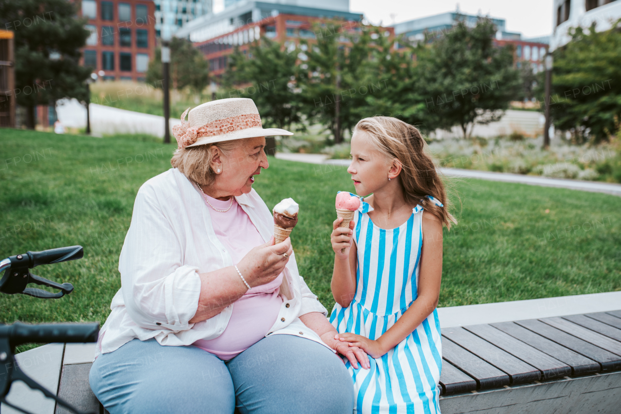 Grandma and granddaugter in the city, sitting on bench. Girl spending time with senior grandmother, during holidays, after school.