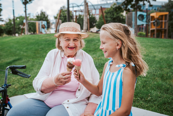 Grandma and granddaugter in the city, sitting on bench. Girl spending time with senior grandmother, during holidays, after school.