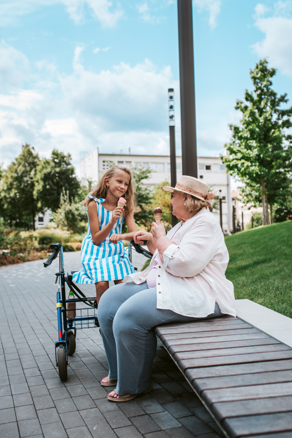 Grandma and granddaugter in the city park. Girl spending time with senior grandmother, during holidays, after school.