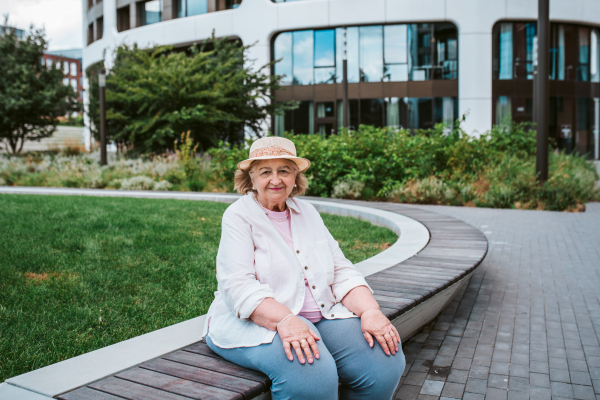 Elderly woman sitting on bench, taking break after long walk. Senior woman running errands, feeling fatigued.