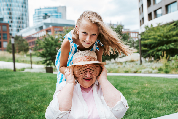 Girl covering grandma's eyes with hands. Granddaughter spending time with senior grandmother, during summer break or after school.