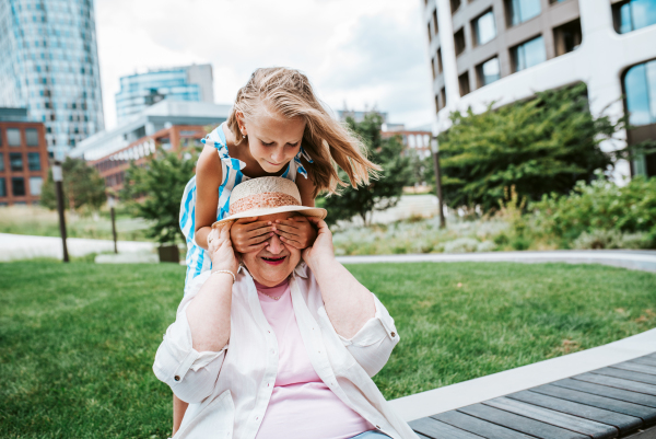 Girl covering grandma's eyes with hands. Granddaughter spending time with senior grandmother, during summer break or after school.