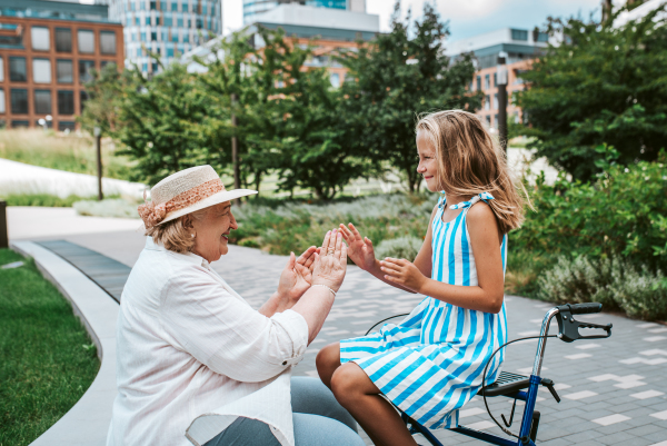 Grandma having fun with granddaugter in the city. Girl sitting on walker, spending time with senior grandmother, during summer break or after school.