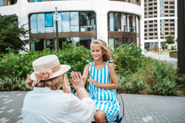 Grandma having fun with granddaugter in the city. Girl sitting on walker, spending time with senior grandmother, during summer break or after school.