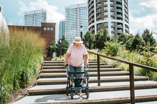 Senior woman walking down the stairs with rollator, running errands.