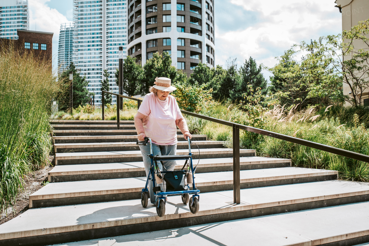 Senior woman walking down the stairs with rollator, running errands.